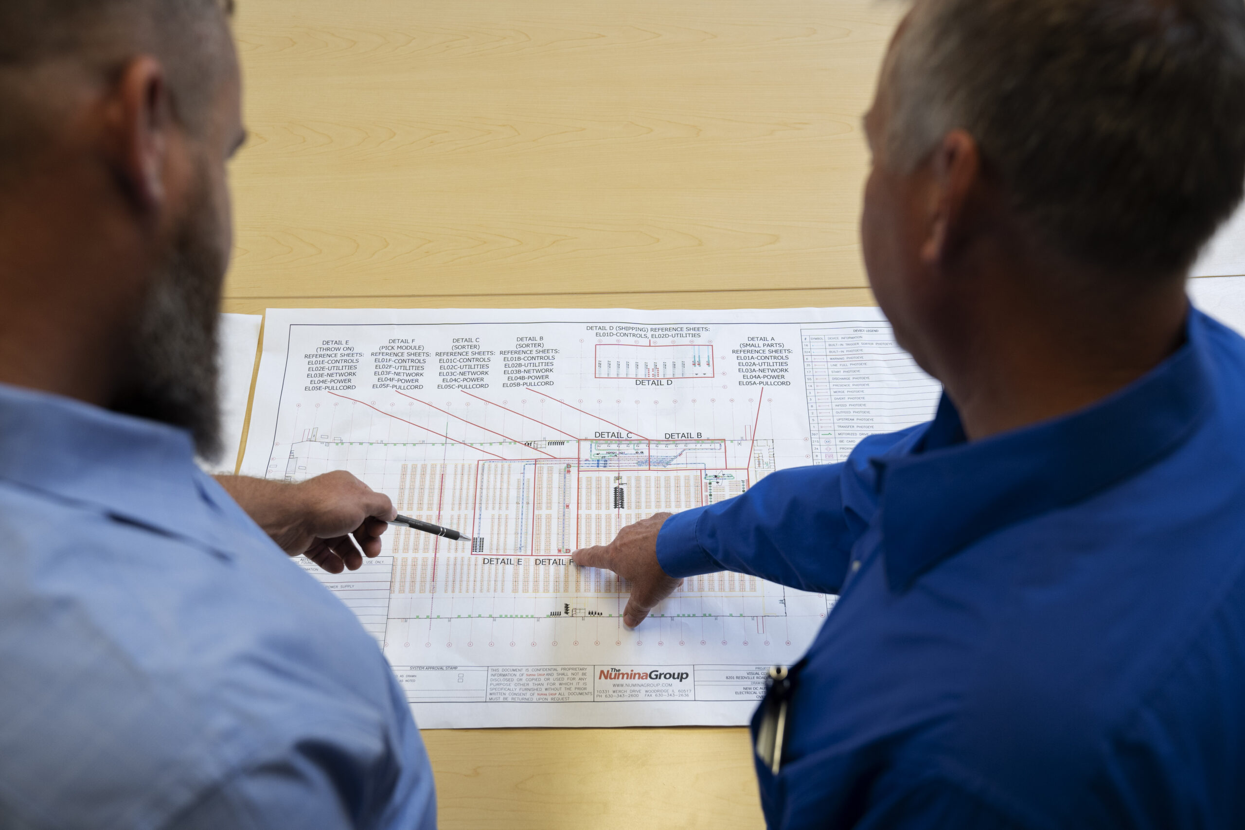 Numina Group engineers reviewing a warehouse layout drawing.