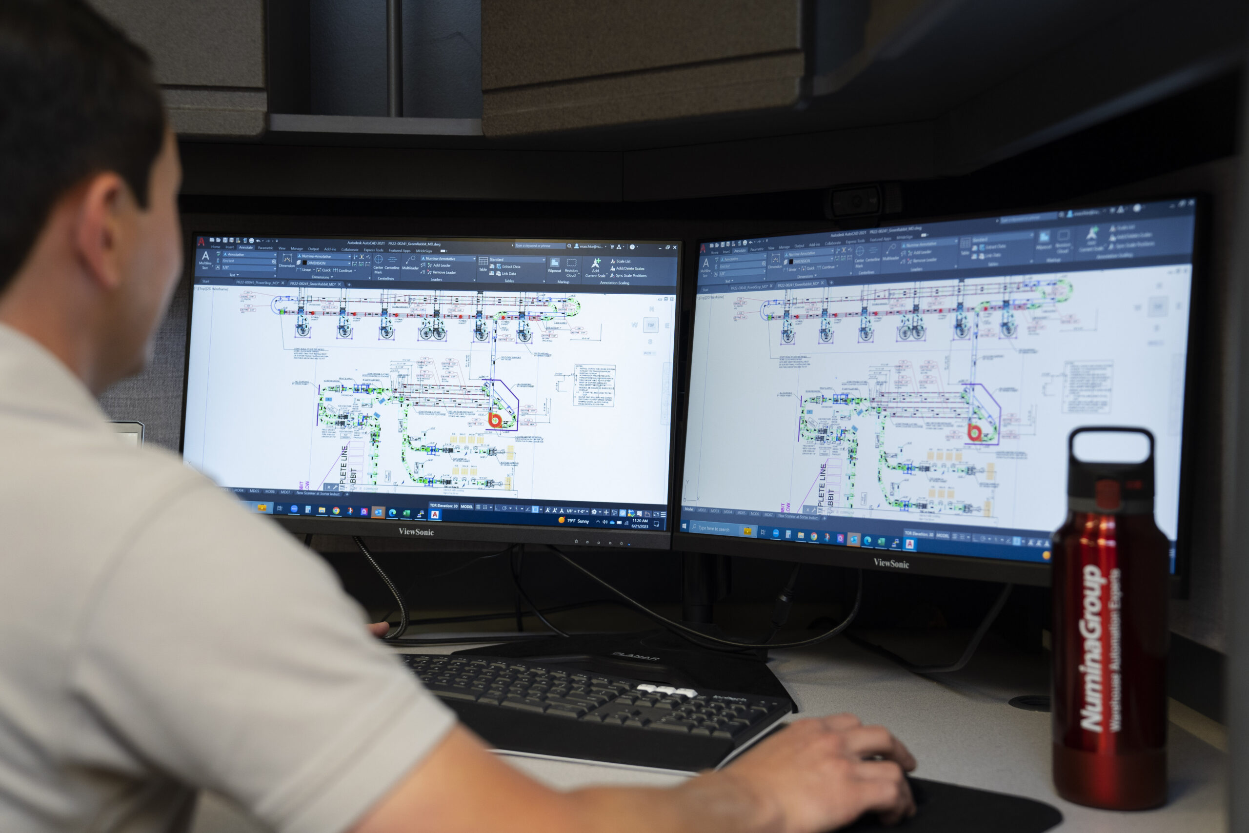 A Numina Group engineer reviewing a conveyor and sortation line layout on dual CAD monitors.